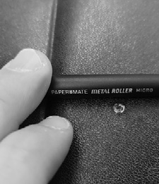 A finger pointing to a small bullet hole in the black cover of Paul Carlson's Bible